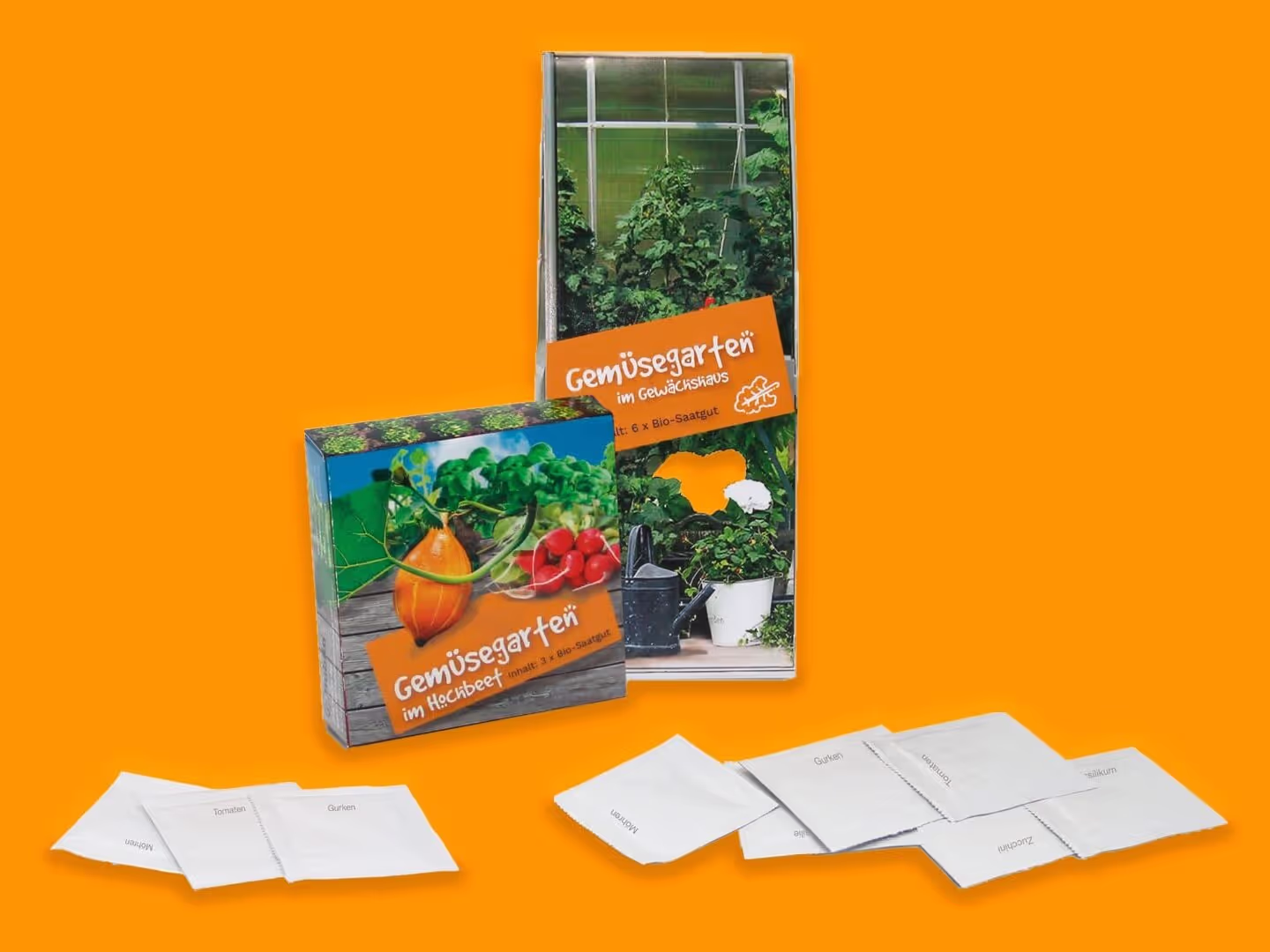 Zwei Gemüsesets mit bunten Verpackungen, auf denen Gemüse und Pflanzen abgebildet sind, werden auf einem orangefarbenen Hintergrund ausgestellt, zusammen mit mehreren kleinen weißen Saatgutpaketen, die davor ausgebreitet sind.