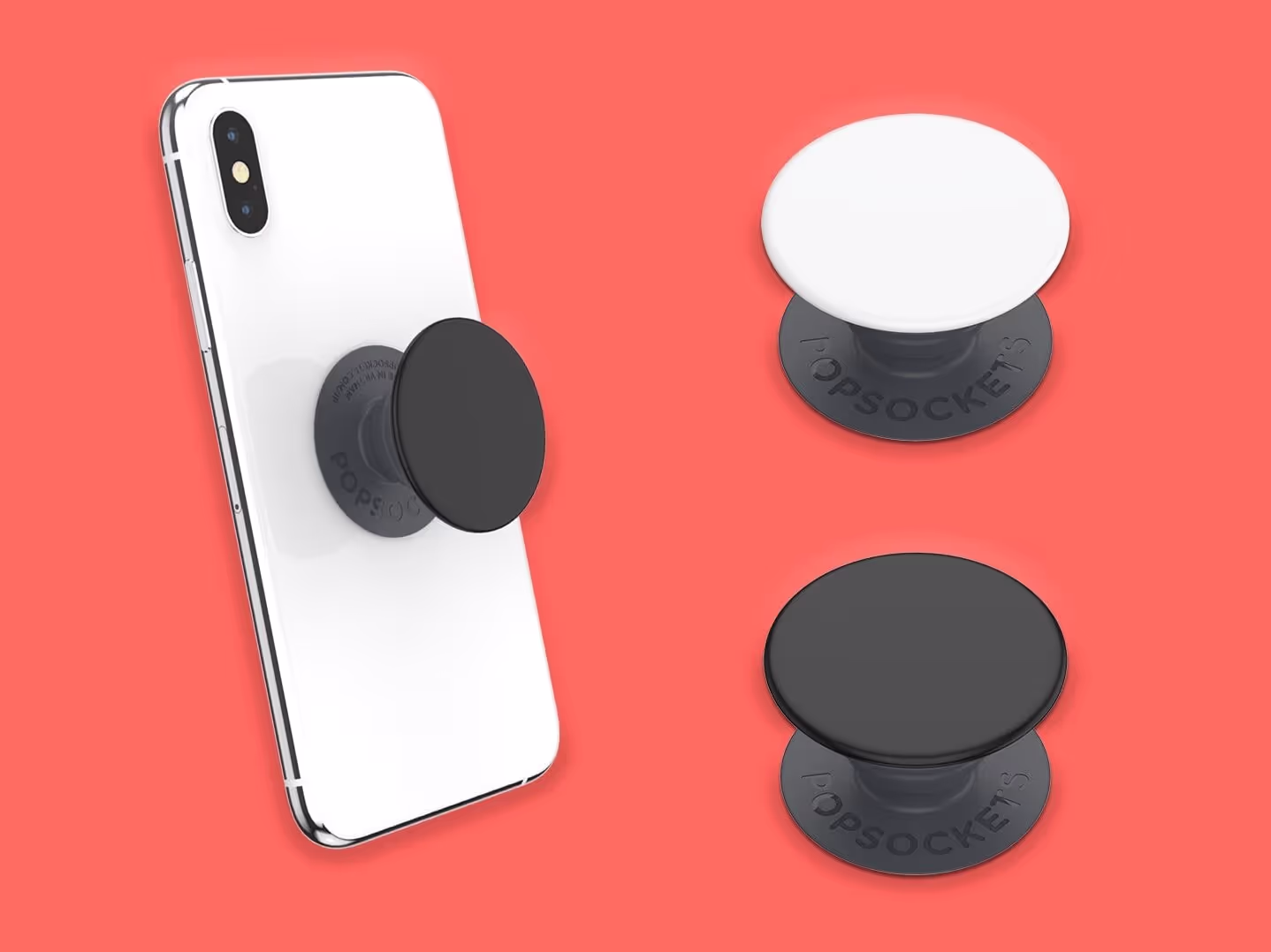 Ein weißes Smartphone mit einem schwarzen PopSocket wird neben zwei PopSockets - einem weißen und einem schwarzen - auf einem korallenroten Hintergrund gezeigt.